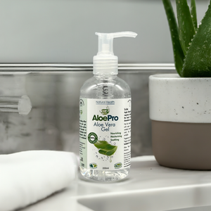 Manuka Honey Direct AloePro aloe vera gel for skin in clear pump bottle beside aloe plant and towel