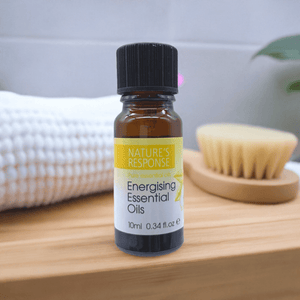 Natures Response tea tree essential oil 10ml amber bottle with black cap on wooden tray beside brush and towel