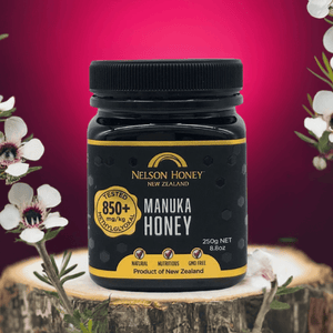 Nelson Manuka honey MGO 850+ 250g black jar by Nelsons Honey on wooden stump with manuka flowers