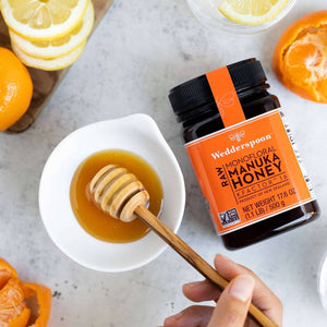 Wedderspoon Raw Manuka Honey KFactor 16 500g Triple Pack jar with honey dipper and citrus fruits