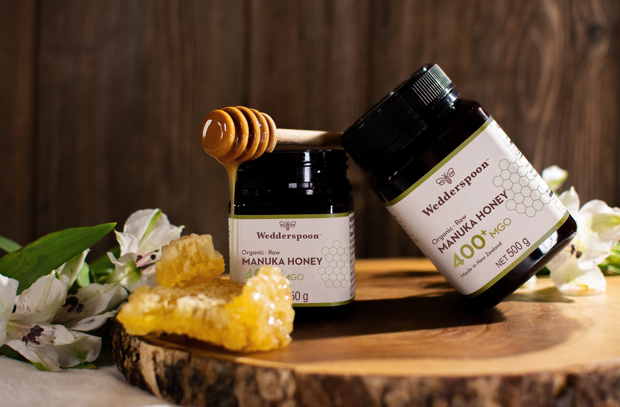 Manuka honey jars with honeycomb and wooden dipper on rustic board Best Raw Organic Manuka Honey UK Traceable Certified Genuine