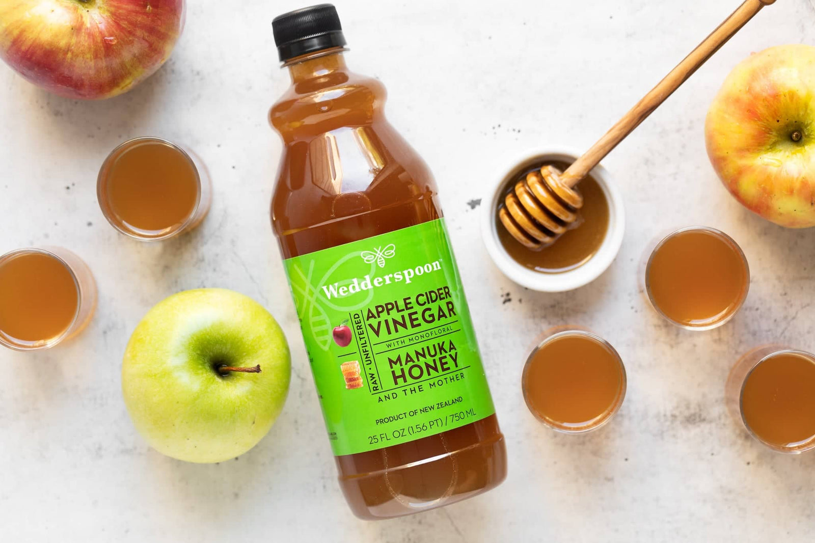 Top view of apple cider vinegar bottle with apples honey and shots illustrating best natural remedies with apple cider vinegar