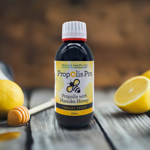 Propolis throat syrup with manuka honey bottle from Manuka Honey Direct on wooden table with lemons and honey dipper