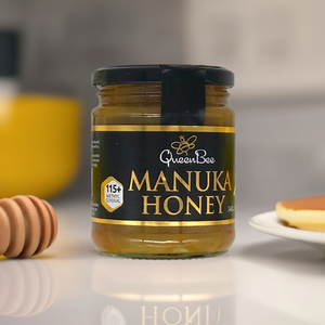 Queen Bee Manuka Honey 340g Glass Jar with black label and golden text on kitchen counter