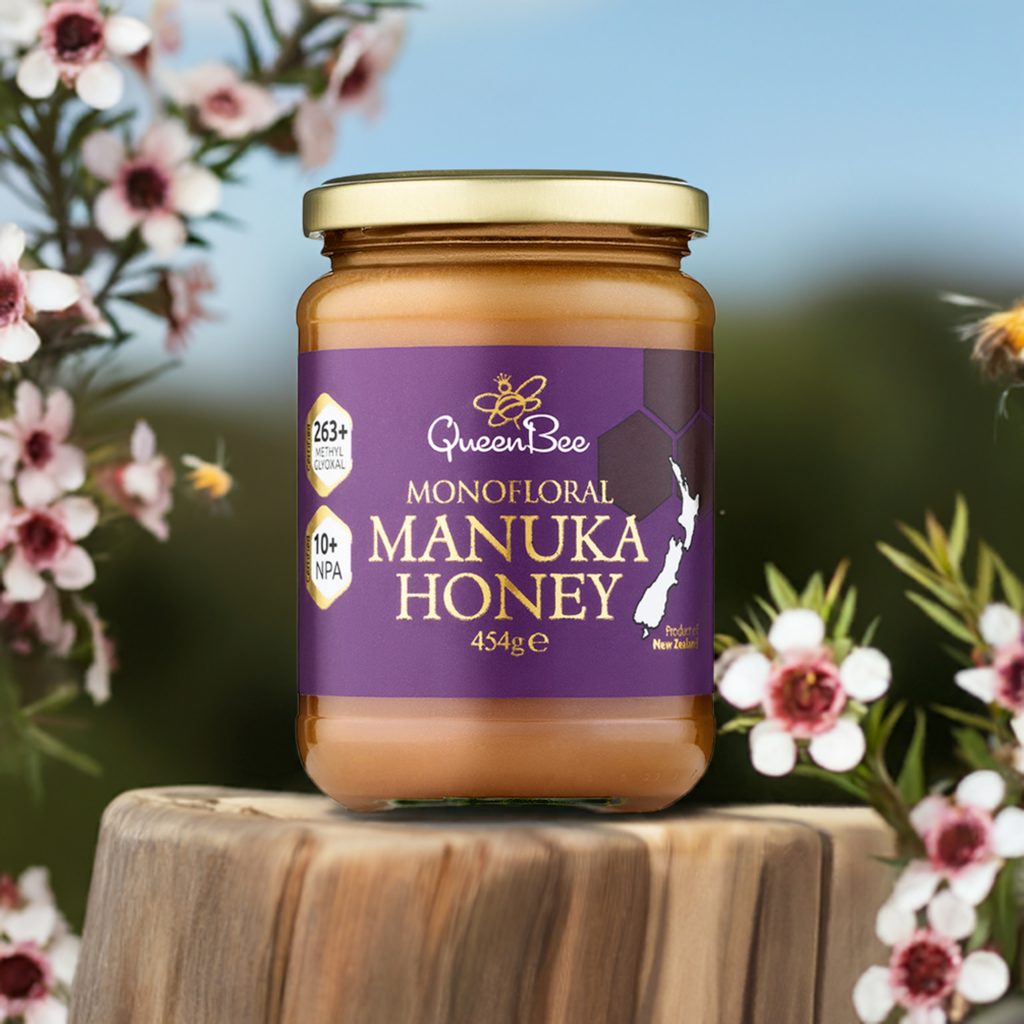Queen Bee Manuka Honey MG 263+ 454g jar with purple label displayed on wood with flowers in background