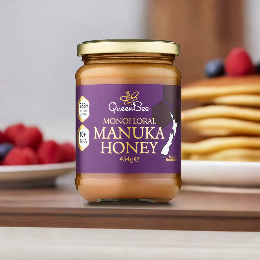 Queen Bee Manuka Honey MG 263+ 454g jar with purple label on wooden table near pancakes and berries
