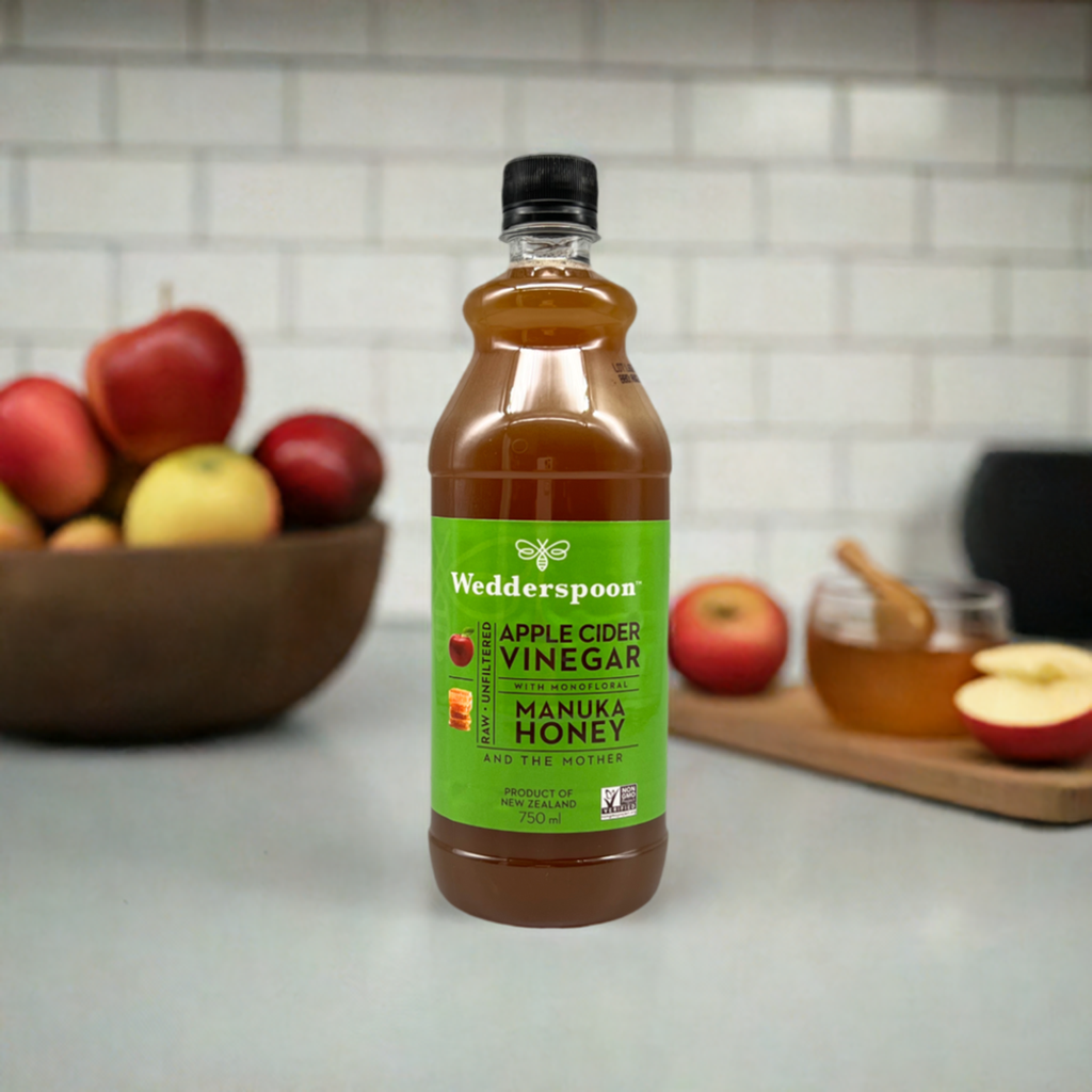 Wedderspoon apple cider vinegar with manuka honey bottle on kitchen counter with apples and honey jar