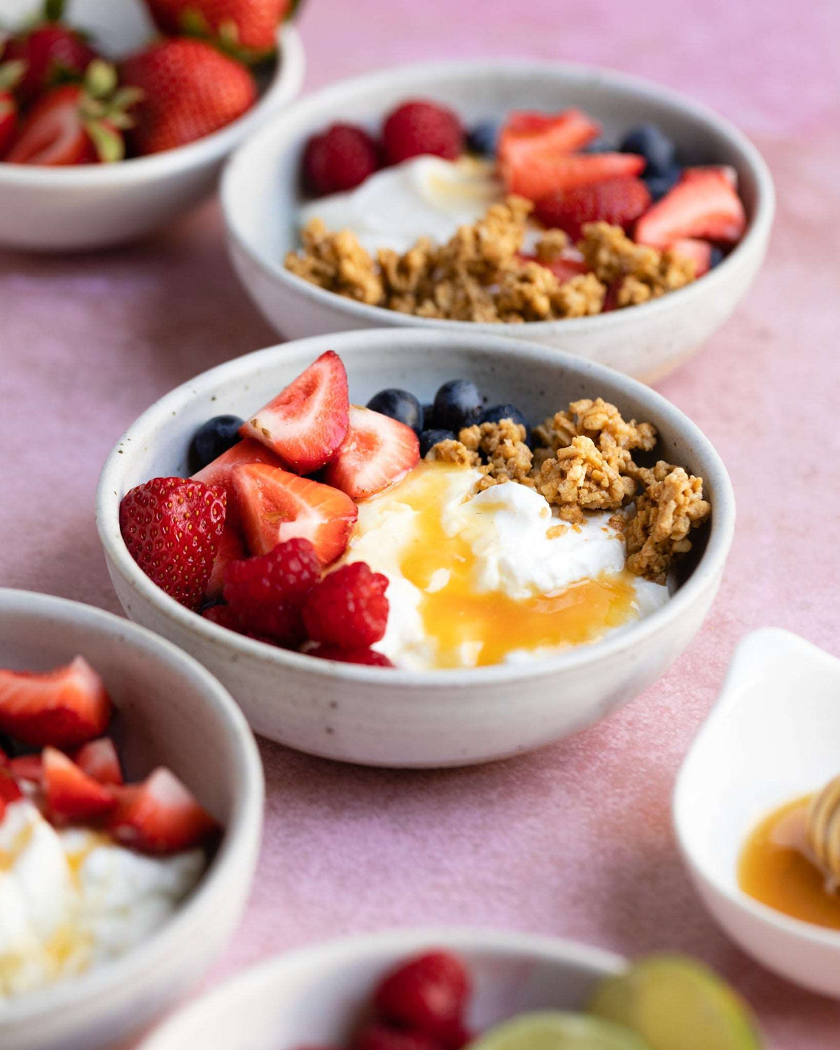 Bowl of granola with fresh berries and yogurt drizzled with Wedderspoon Raw Manuka honey KFactor 12
