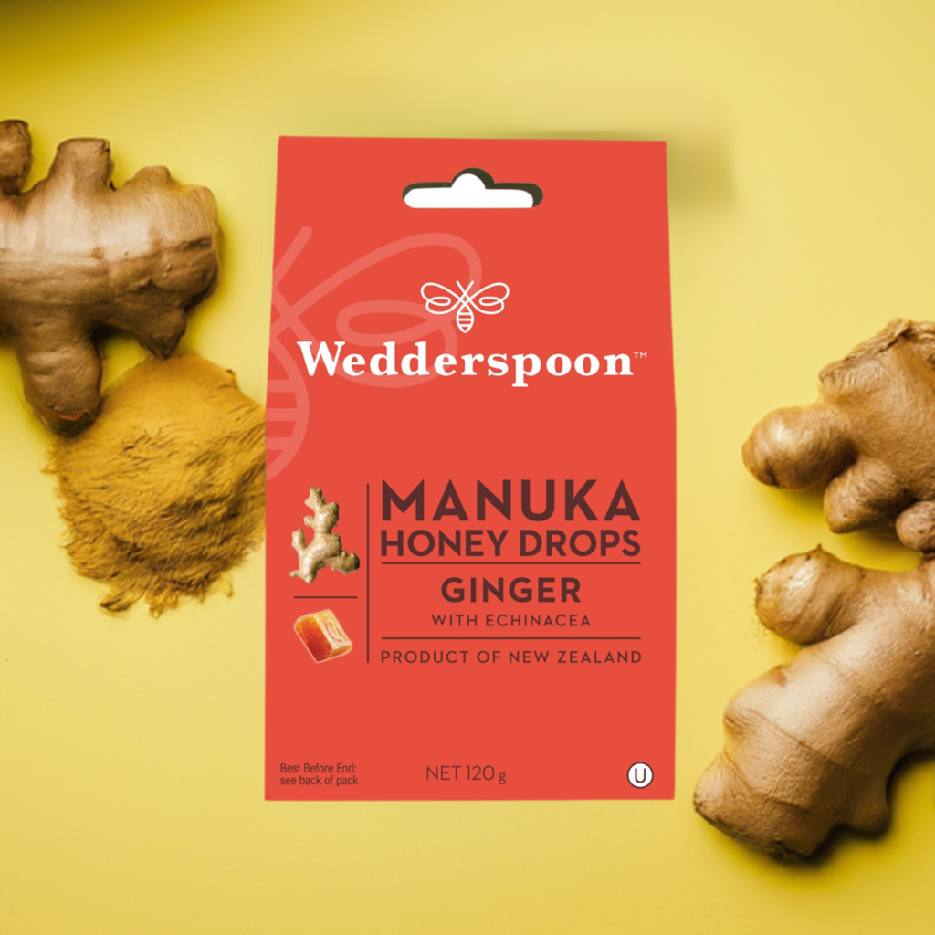 Wedderspoon Manuka honey drops ginger triple pack throat lozenges with fresh ginger roots on yellow background