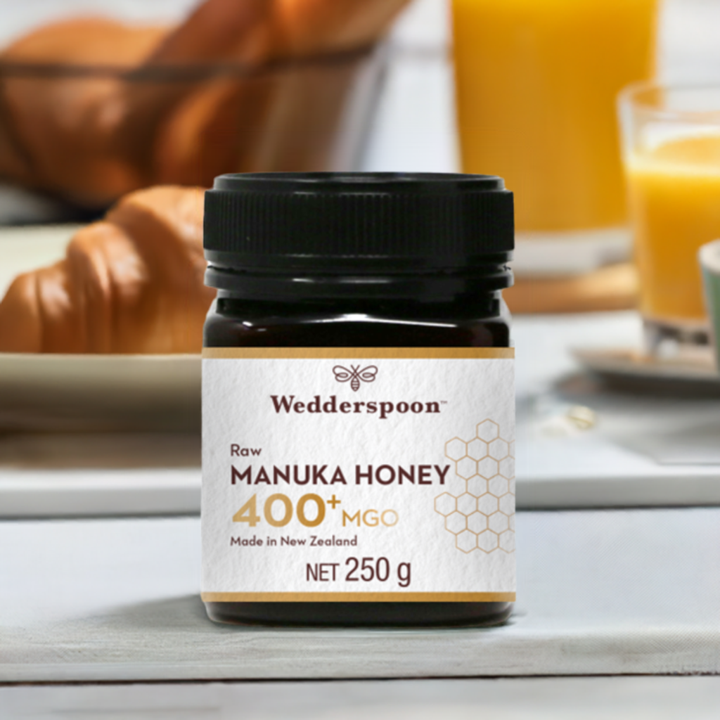 Wedderspoon Raw Manuka Honey 400 MGO 250g Unpasteurised jar on table with croissants and orange juice