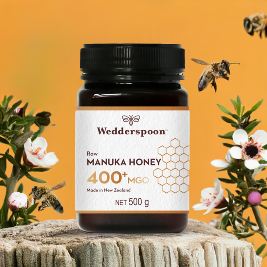 Wedderspoon Raw Manuka Honey 400 MGO 500g jar on wooden stump with bees and flowers