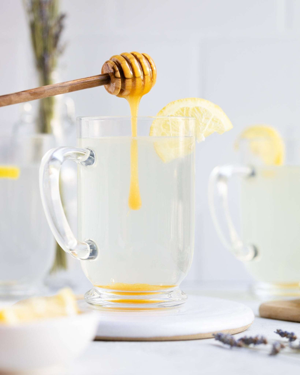 Wedderspoon Raw Manuka honey KFactor 12 500g drizzling into clear glass mug of lemon hot water