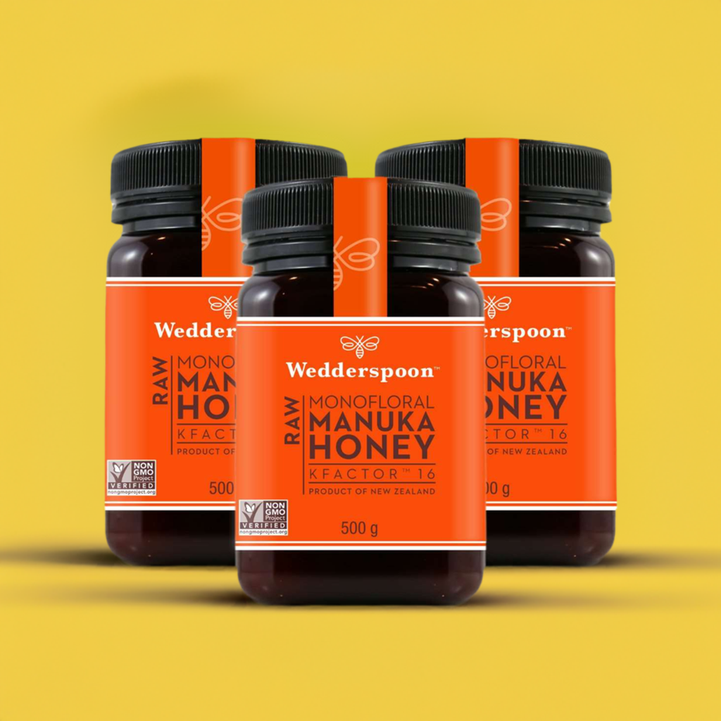 Wedderspoon Raw Manuka Honey KFactor 16 500g Triple Pack with orange label jars on yellow background